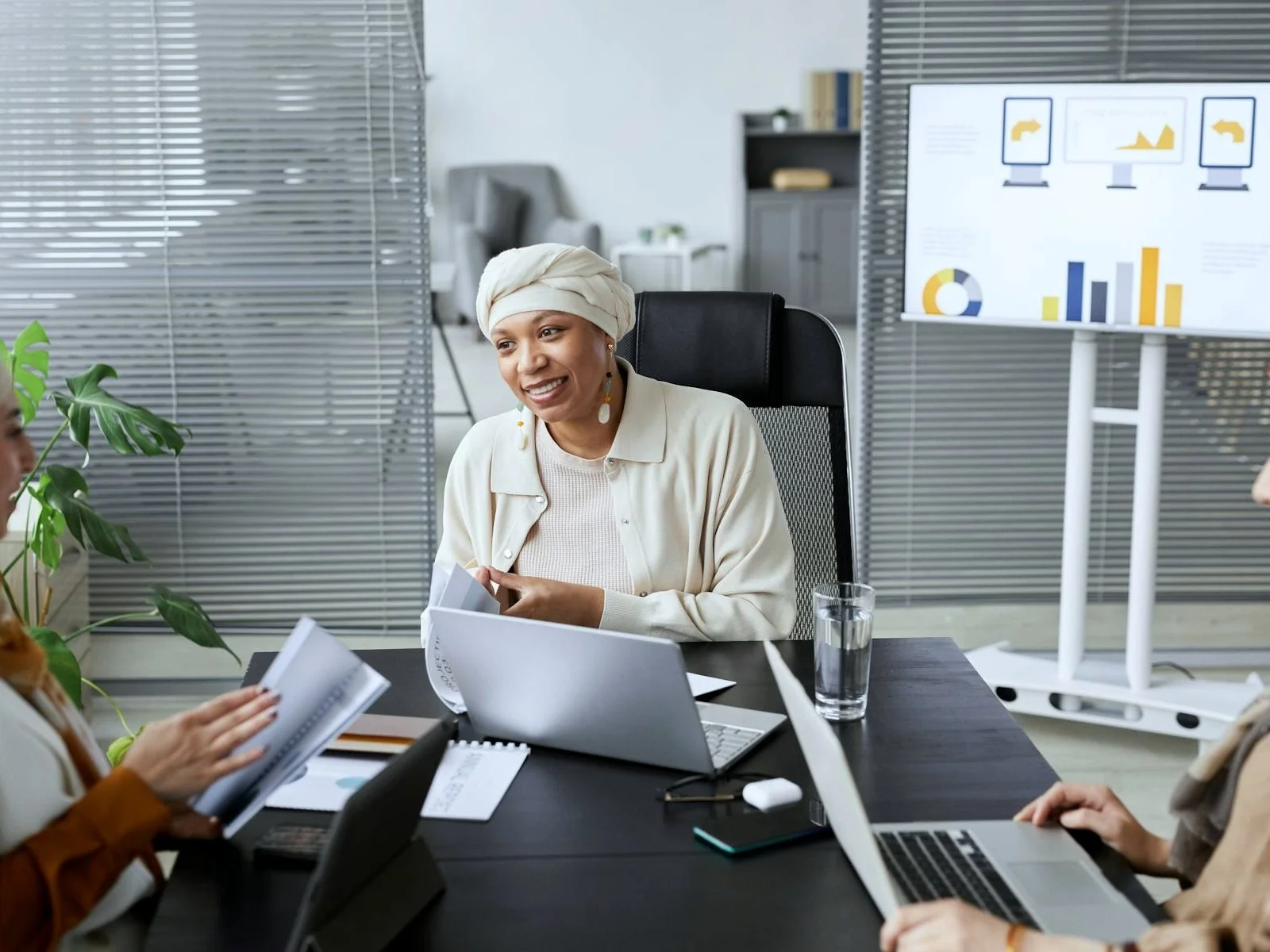 Business team in a neutral office meeting with laptops and performance charts